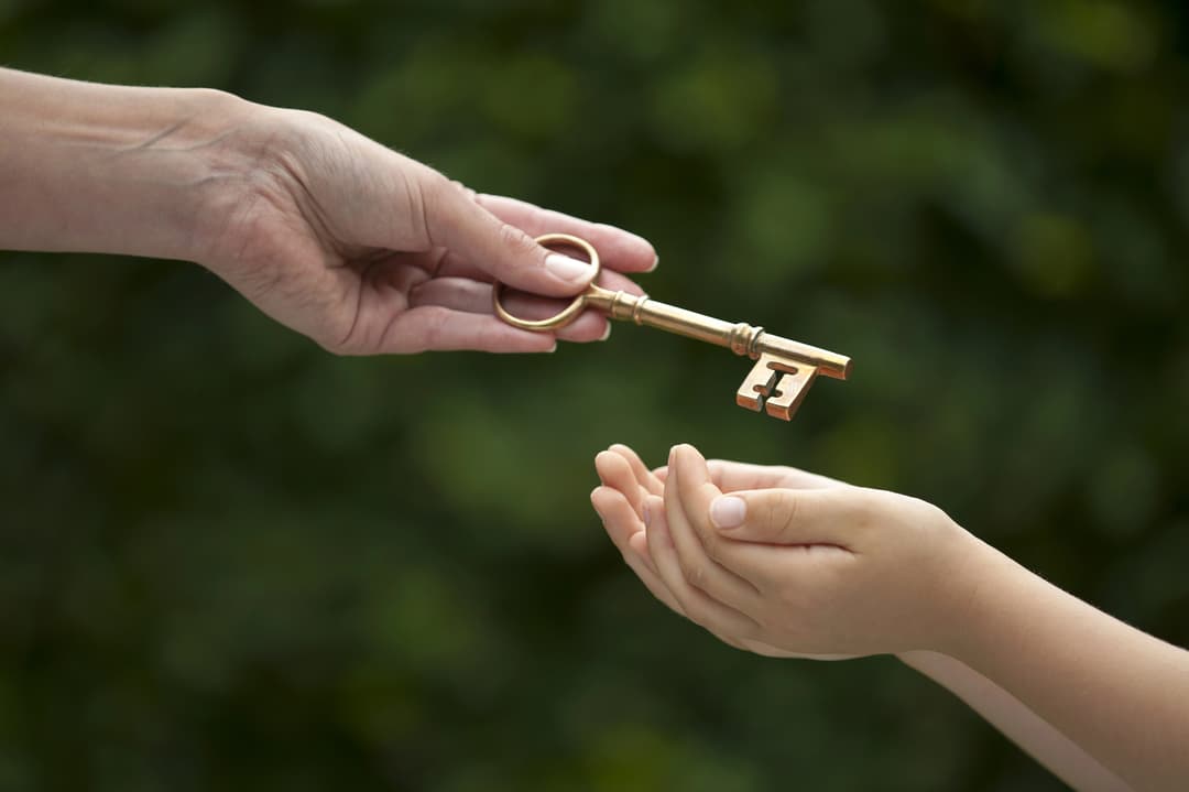 An older hand passing a key to a younger hand — giving Final Peace to aging parents as an end-of-life planning gift